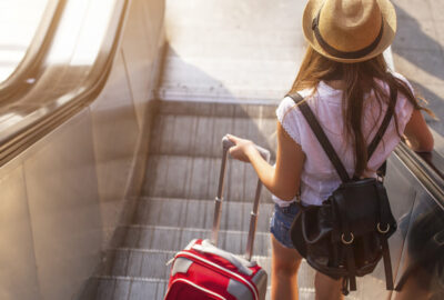 Young,Girl,With,Suitcase,Down,The,Escalator.